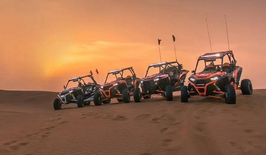 Four Polaris dune buggies lined up beautifully at golden hour sunset in the Abu Dhabi desert, perfect for an unforgettable desert buggy tour adventure.